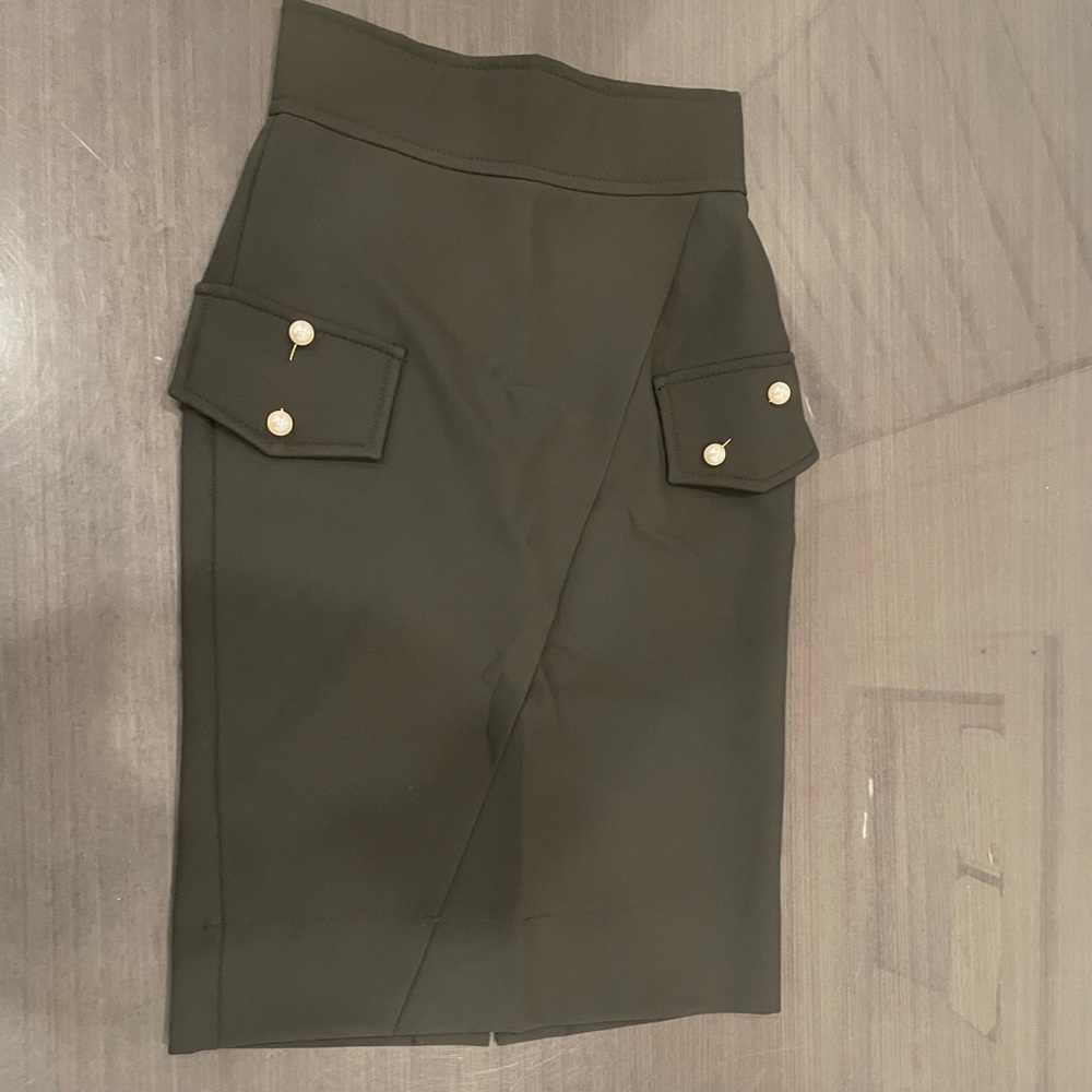 Black pencil skirt with gold pearl pins on the packets and a slit on the back.